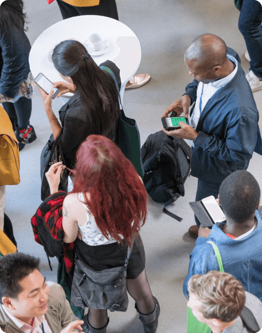 People standing in line at a conference, while using their mobile devices.