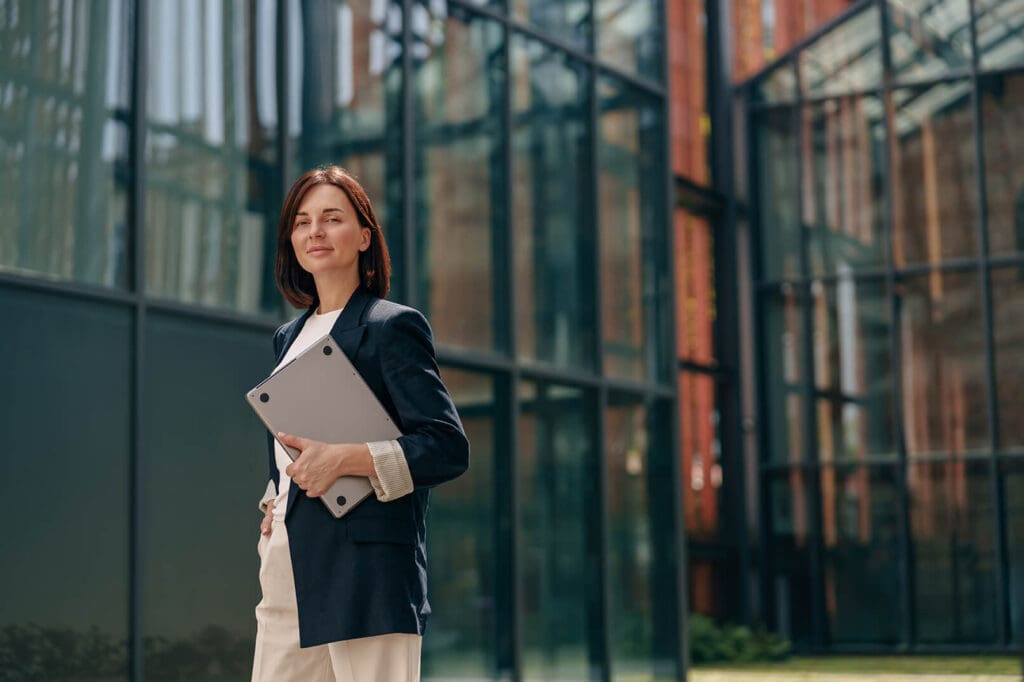 business woman with laptop by office buildings