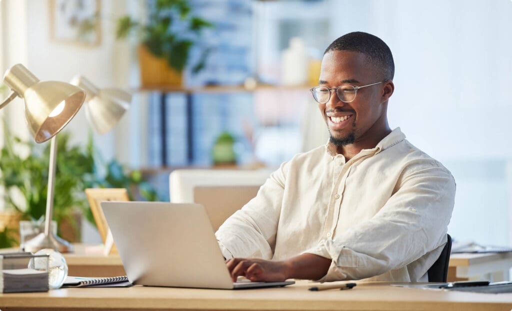 Businessman smiling while working on laptop.